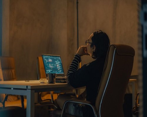 Person changing sitting posture while working on a laptop at a home desk