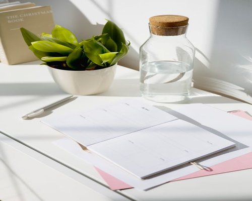A glass of fresh water on a desk next to a notebook